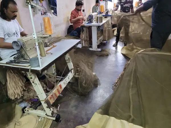 Nirmal Textiles factory — workers stitching Ganga-Gita machardani on industrial machines